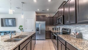 A modern kitchen with granite countertops, stainless steel appliances, and dark cabinetry.