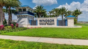 A sign for Windsor Island Resort with a modern building and palm trees.
