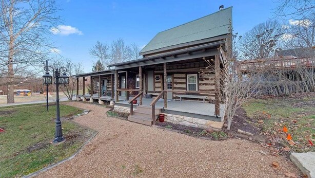 A rustic log cabin with a porch and a green roof. - Historic Augusta Cabin | Wine Country & Fire Pit (Augusta)