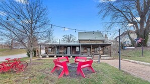 A rustic log cabin with a porch, a fire pit, and red chairs. - Historic Augusta Cabin | Wine Country & Fire Pit (Augusta)