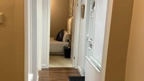 A narrow hallway with wooden flooring and a black doormat at the entrance. - Dunfermline GF flat, 5 mins to Train St. & High St

 (Dunfermline)