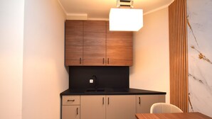 A modern kitchen with wooden cabinets, a black countertop, and a wooden dining table. - stay with legends (Hamburg)