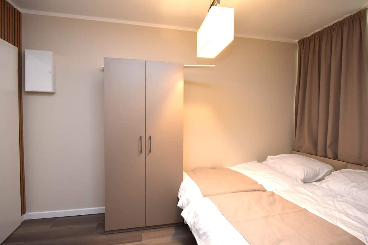 A bedroom with a bed, a wardrobe, and a ceiling light.