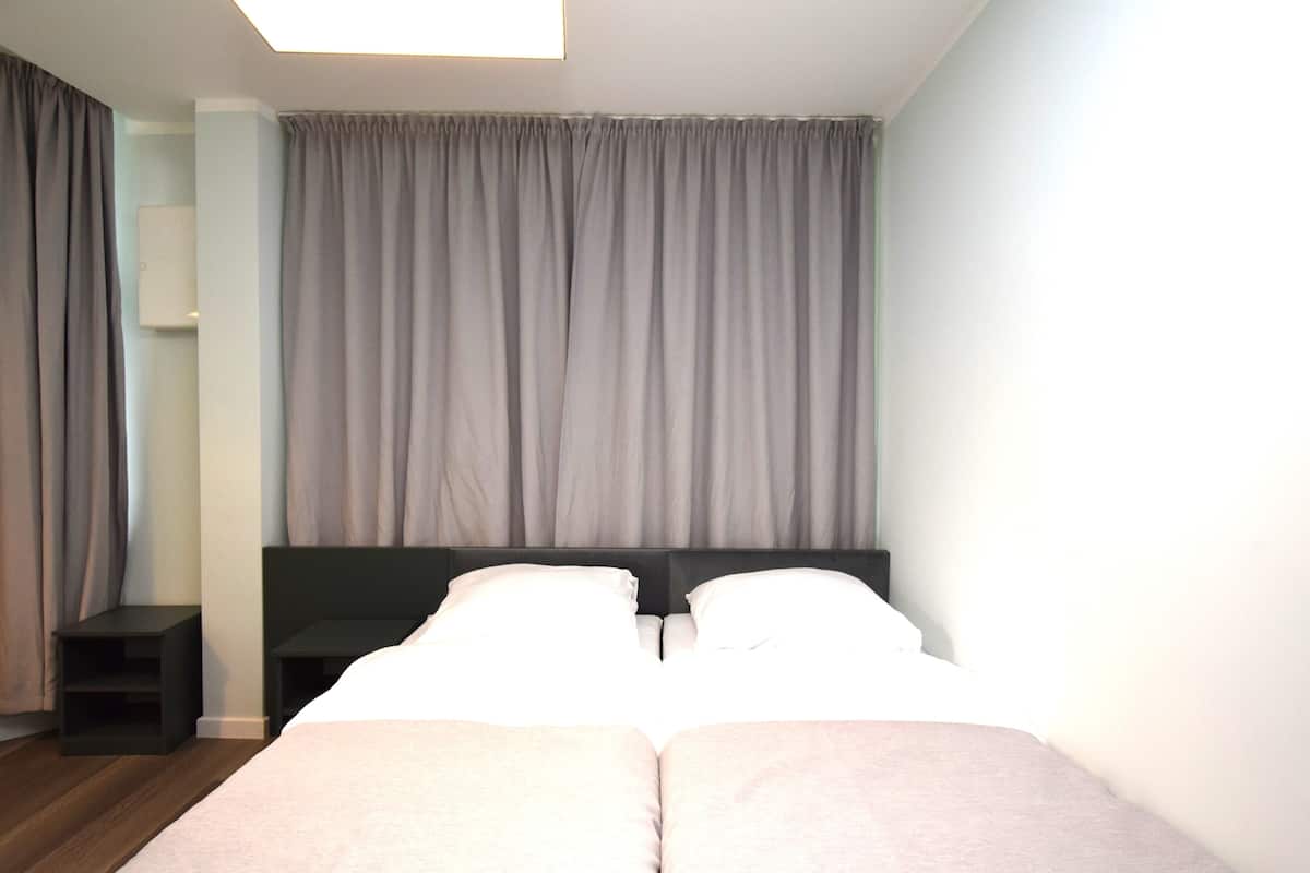 A bedroom with a bed, two bedside tables, and a large window with curtains.