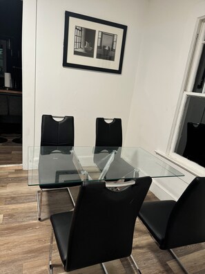 A modern meeting room with a glass table and black chairs, a framed picture on the wall, and a window with blinds. - Cozy 3-bedroom house in fabulous Decatur , AC, WiFi (Decatur)