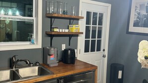 Une cuisine dotée d’un plan de travail en bois, d’une machine à café, d’un lave-vaisselle et d’une étagère contenant des récipients en verre.