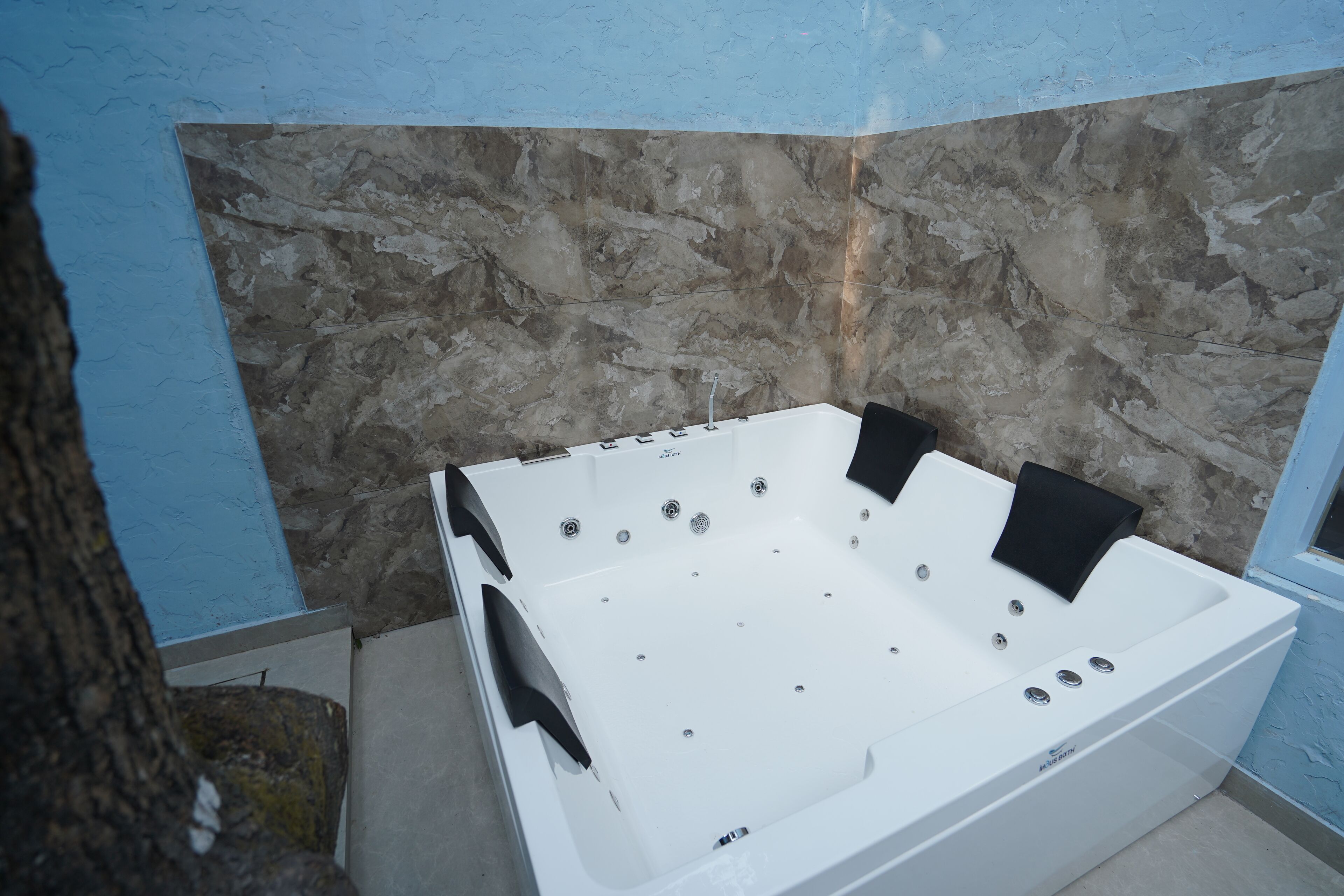 Una bañera blanca con múltiples chorros frente a una pared de piedra.