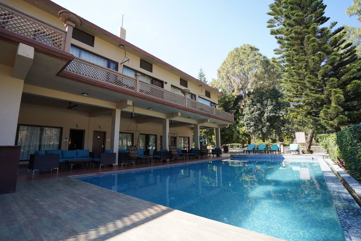 A hotel with a swimming pool, outdoor seating, and a covered balcony.