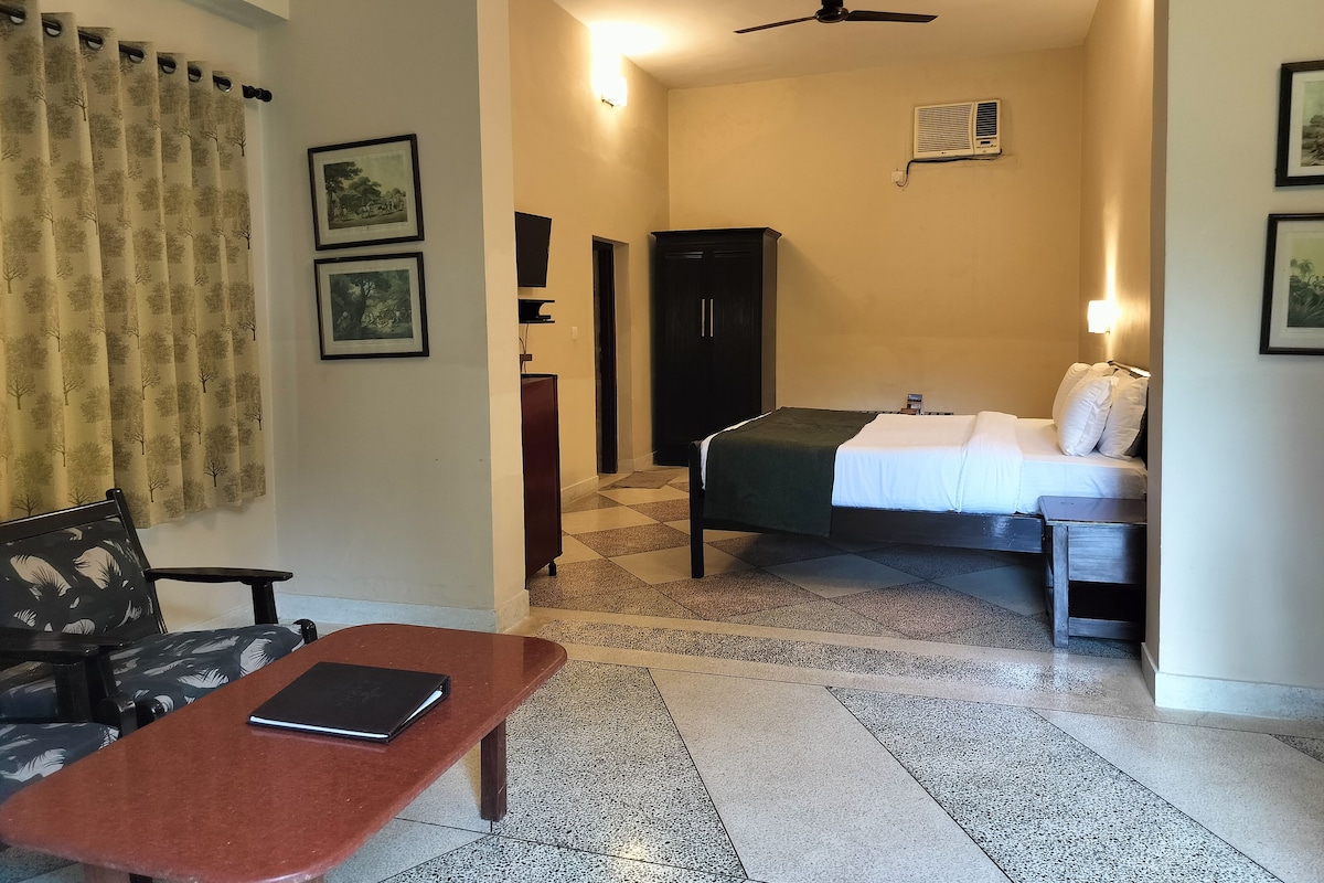 Ein Hotelzimmer mit Bett, Schreibtisch, Stuhl, Kleiderschrank und Deckenventilator.