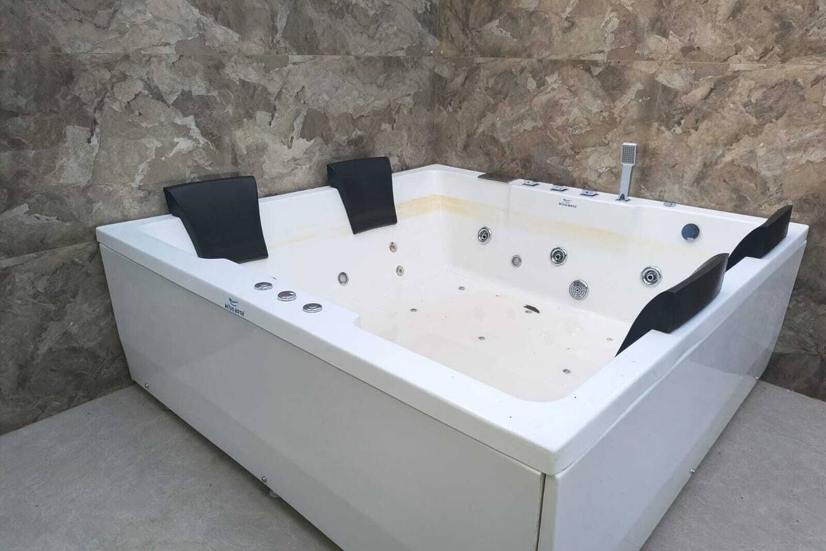 A rectangular hot tub with a white exterior, black footrests, and multiple jets.
