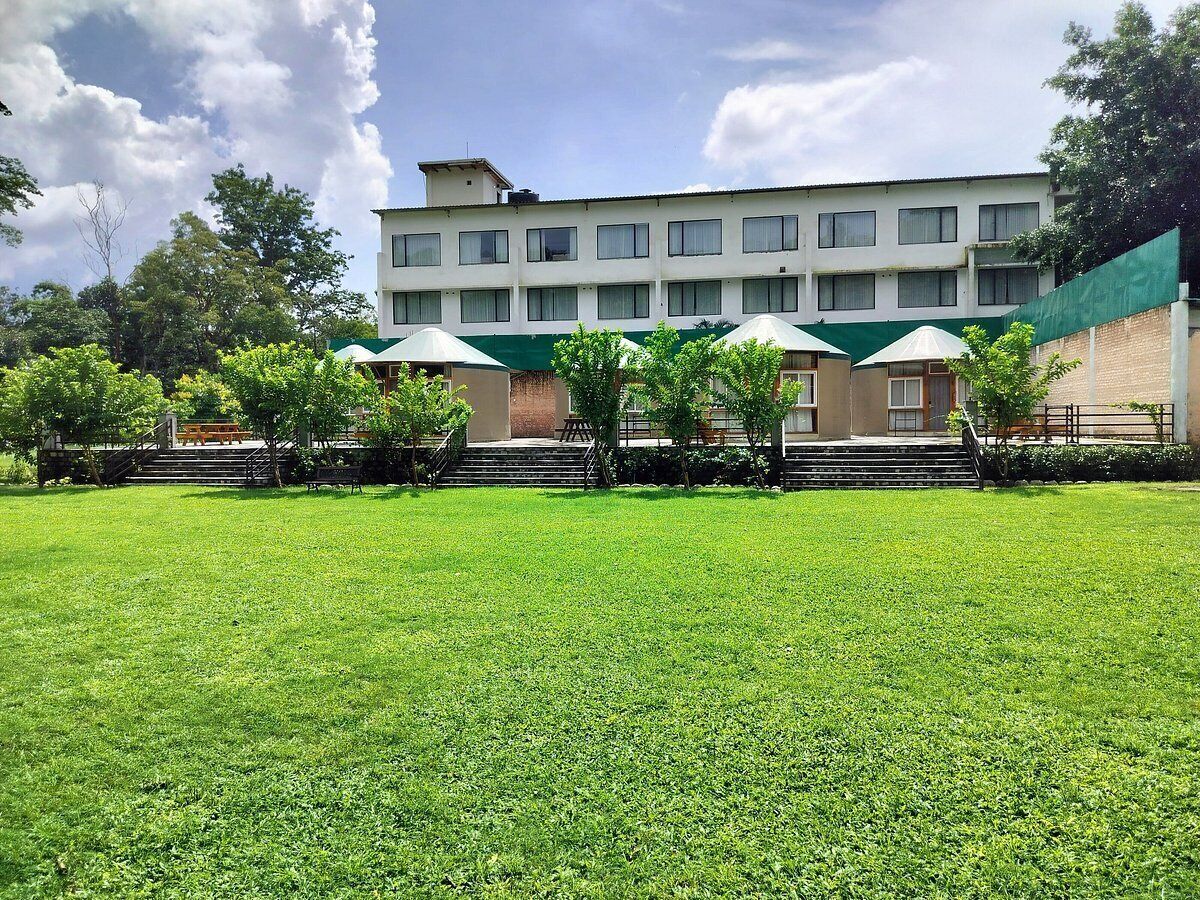 A building with a flat roof, multiple windows, and a green awning over a seating area.