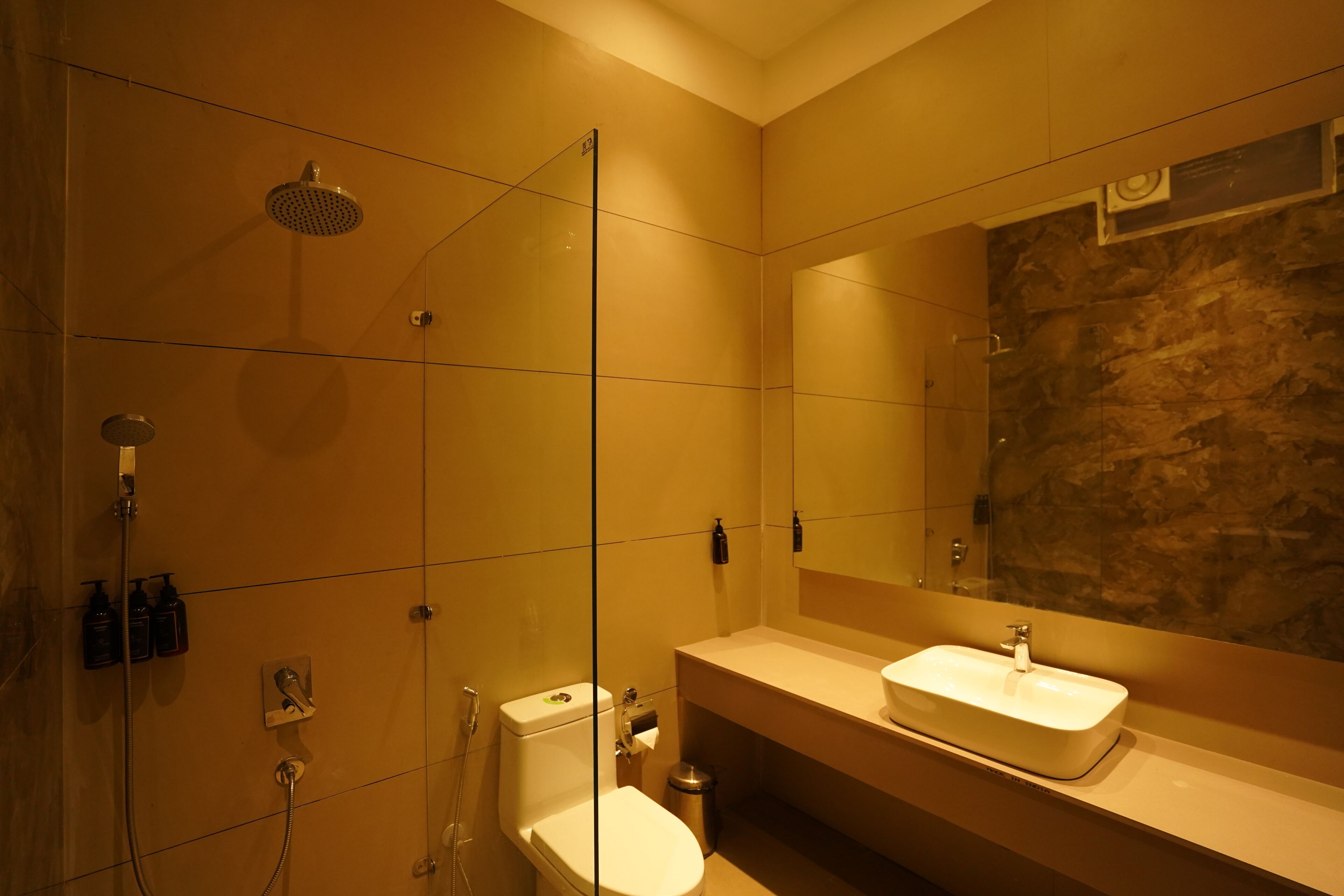 A bathroom with a glass-enclosed shower, a white sink, and a mirror with a stone backsplash.