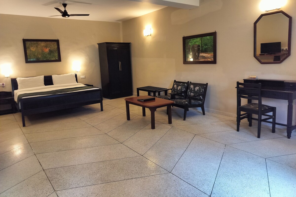 Habitación de hotel con cama, escritorio, silla, armario y dos luces fijadas a la pared.