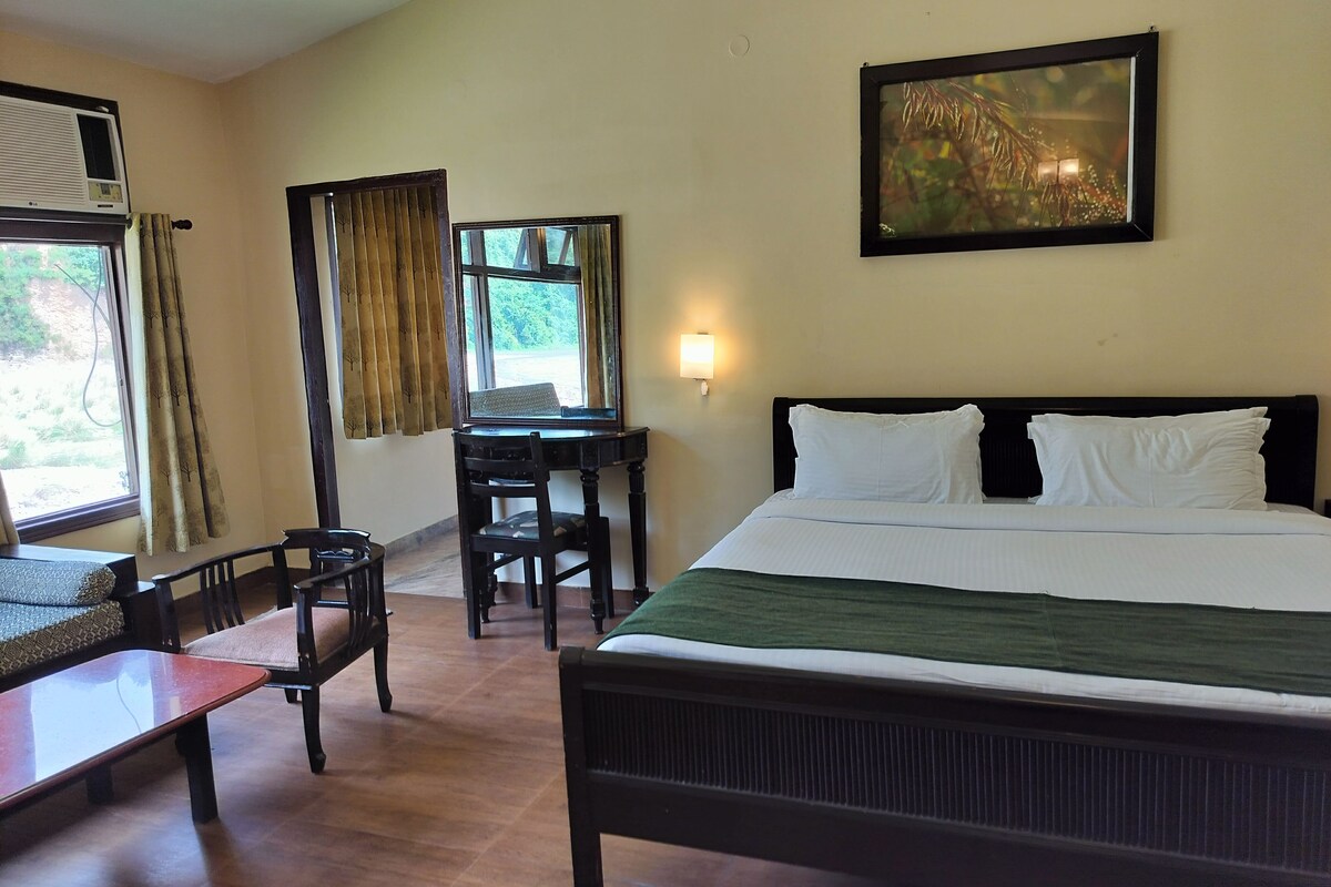 A hotel room with a bed, a desk, a chair, and a window with curtains.