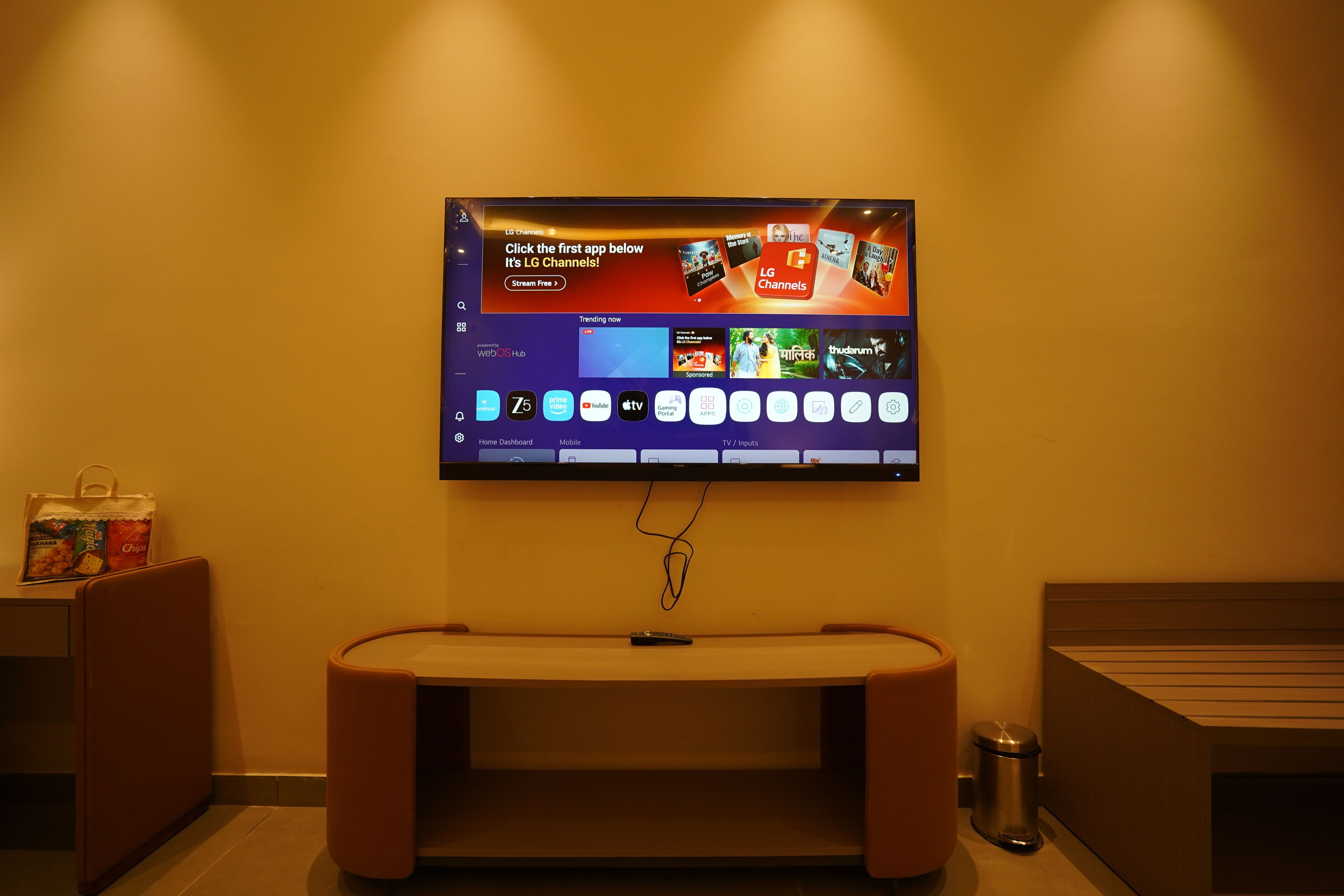 A television mounted on a wall displaying a streaming service interface with various channel options.