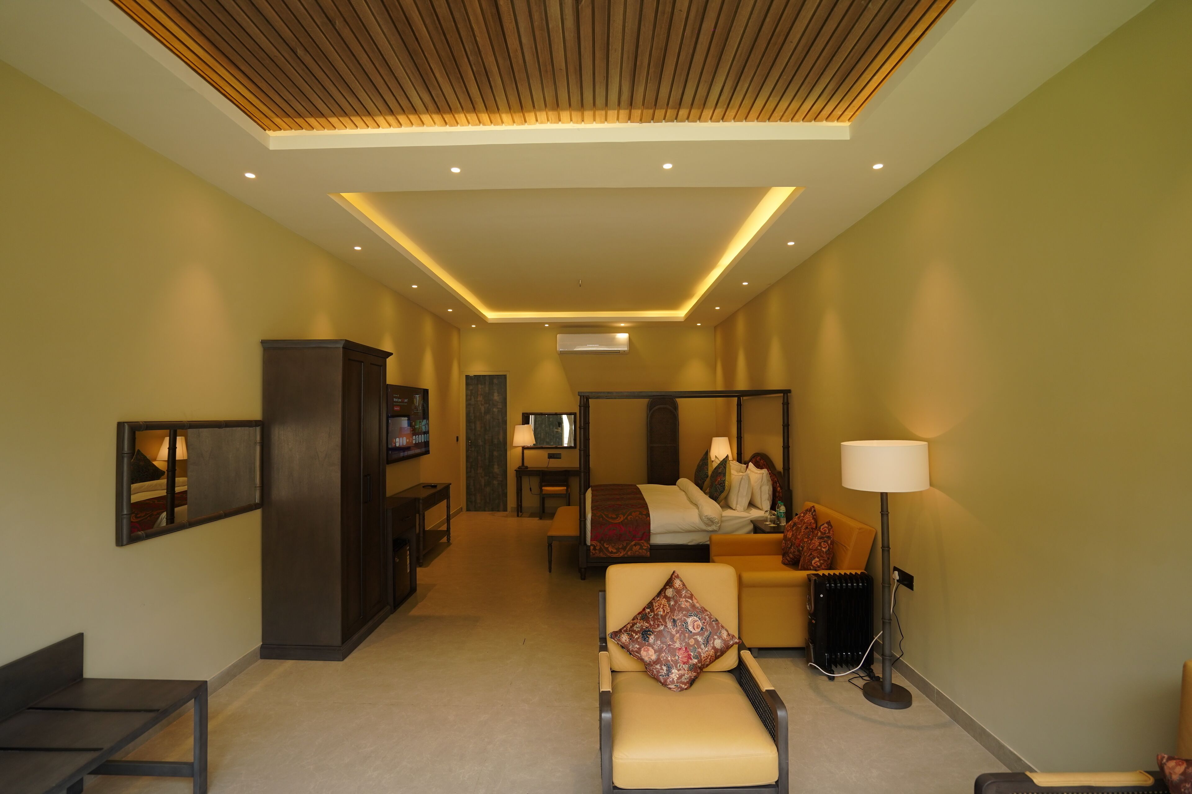 A hotel room with a bed, a sofa, a chair, a desk, and a TV.