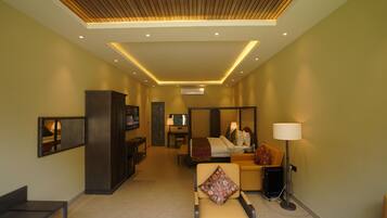 A hotel room with a bed, a sofa, a chair, a desk, and a TV.