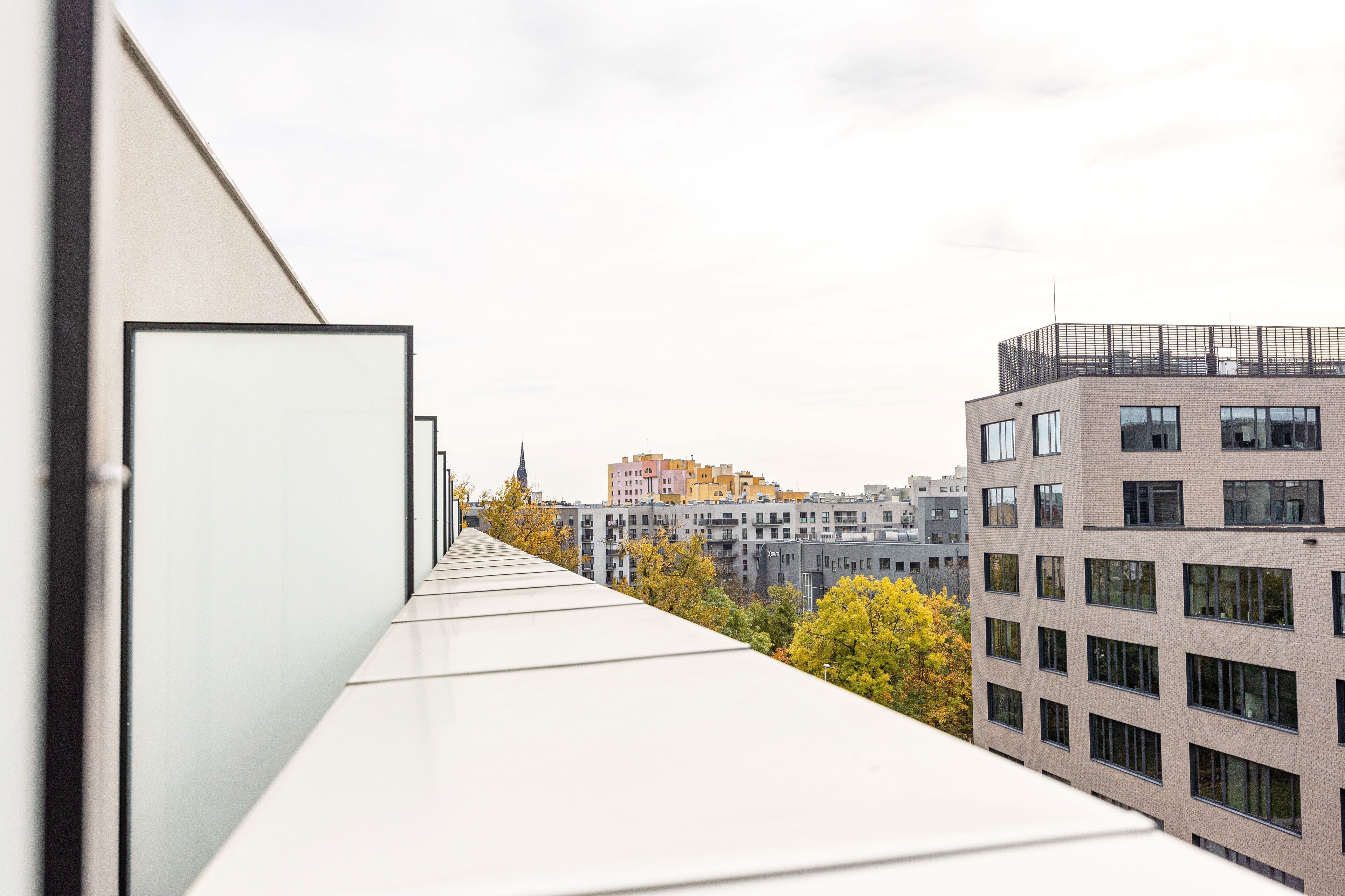 A modern building with a flat roof and a view of other buildings in the background.