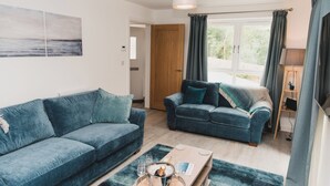 A living room with two blue sofas, a coffee table, and a painting on the wall.