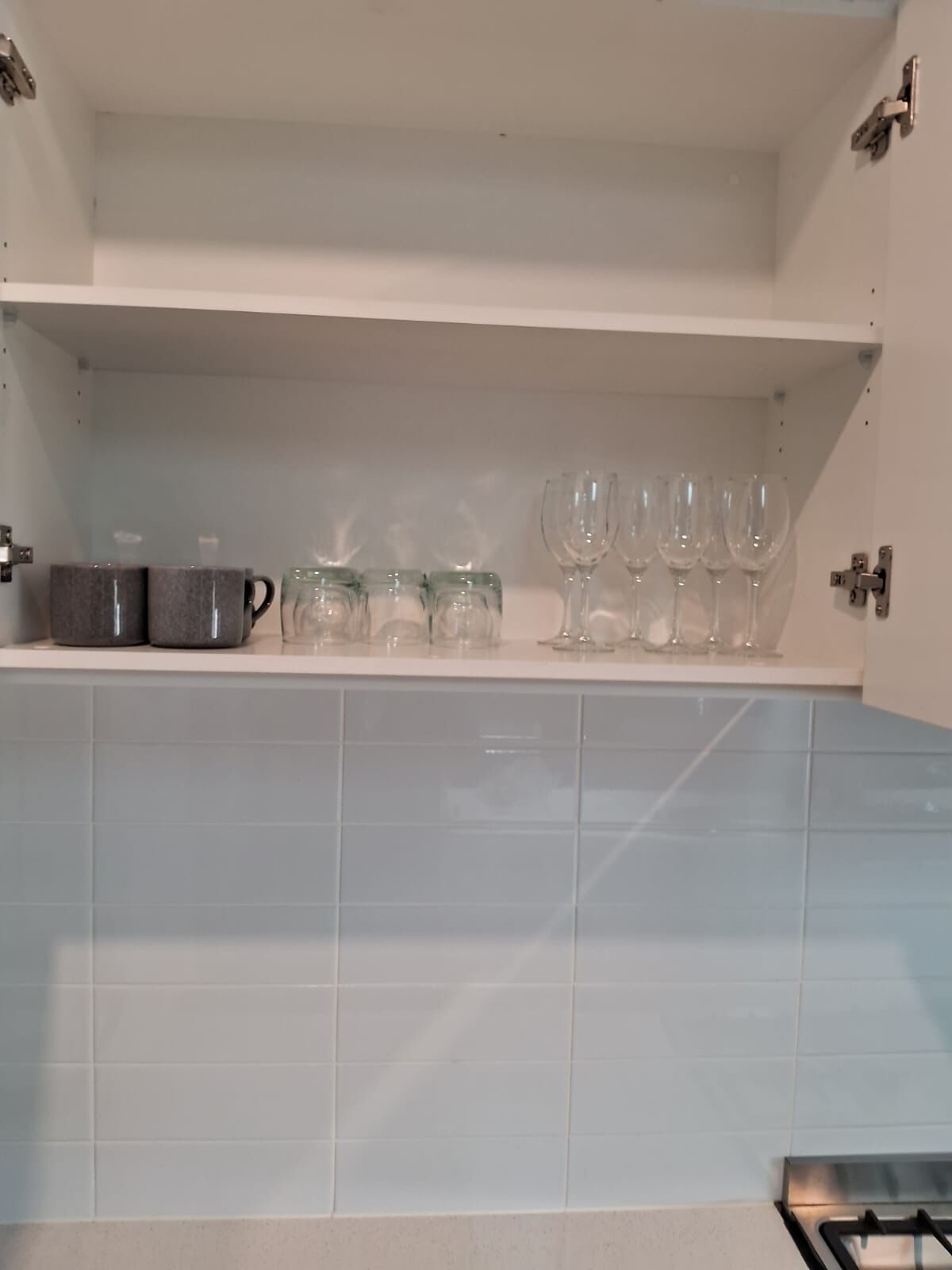 Una cocina con encimera blanca, estufa y un estante con utensilios de cocina.