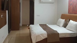 Un dormitorio moderno con una cama, ventilador de techo, aire acondicionado y televisor en la pared.