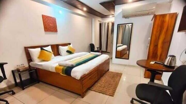 Una habitación de hotel con cama, escritorio, silla, espejo y una mesita.