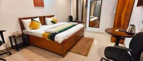 Ein Hotelzimmer mit Bett, Schreibtisch, Stuhl, Spiegel und einem kleinen Tisch.