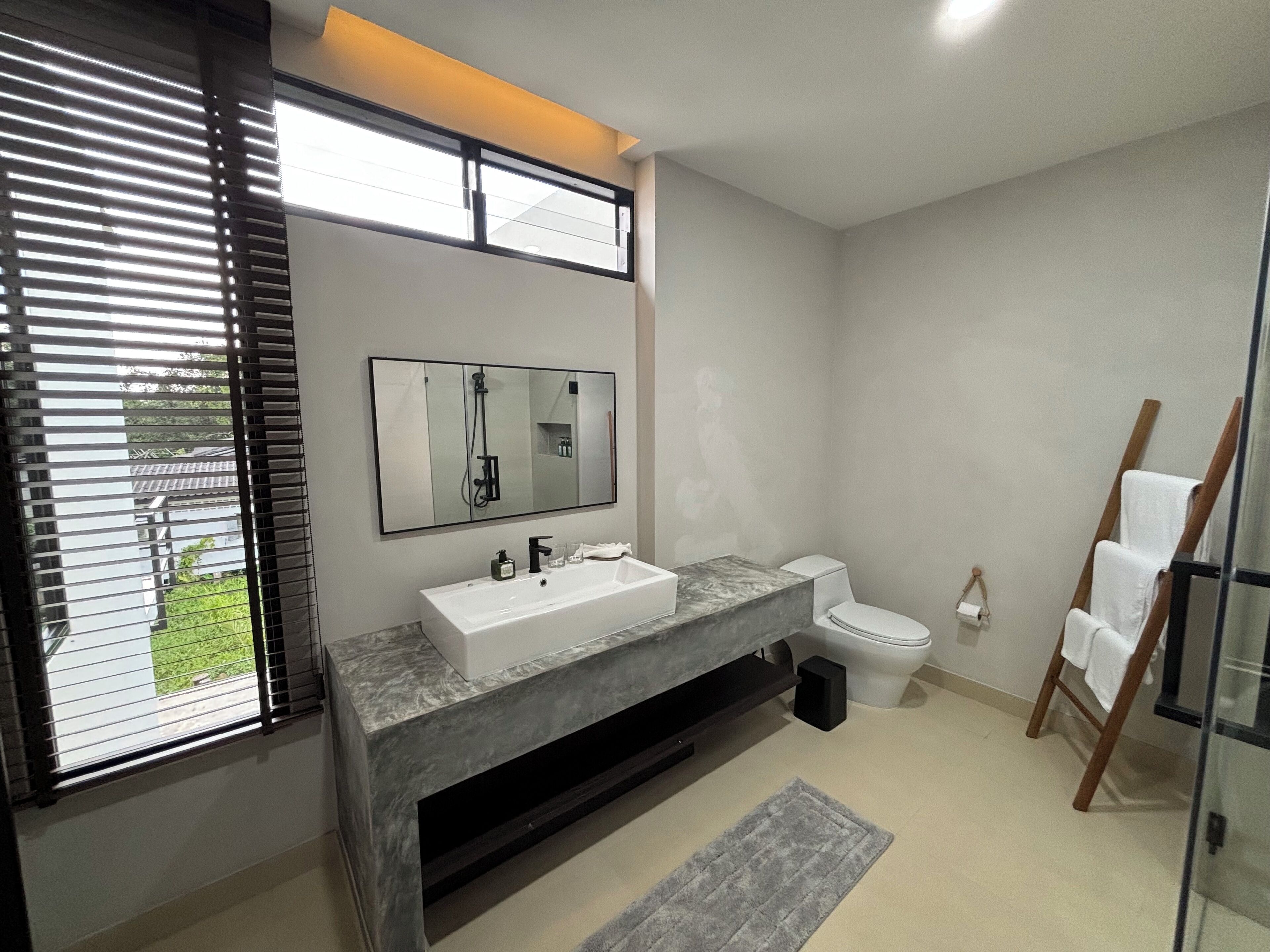 A modern bathroom with a large mirror, a white sink, and a toilet.