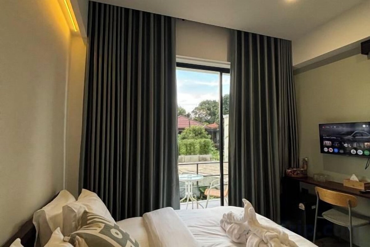 Quarto de hotel com cama, escrivaninha, cadeira, televisão e vista para o exterior.