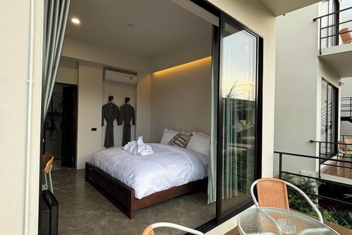 Un dormitorio con cama, una puerta de cristal que da a un balcón y una silla.