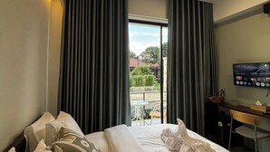 Een hotelkamer met een bed, een bureau, een televisie en uitzicht op de omgeving.