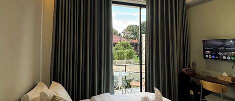 Habitación de hotel con cama, escritorio, televisor y vista al exterior.