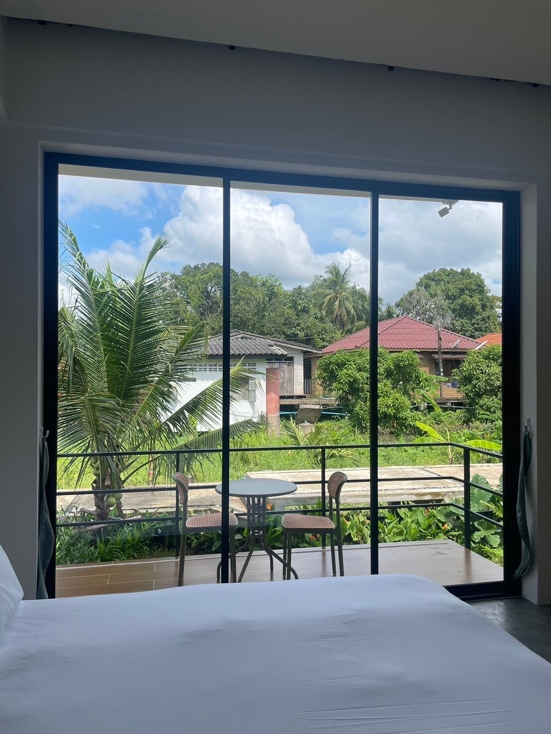 Habitación de hotel con un amplio ventanal corredero que da a un balcón exterior con una mesa y sillas.