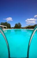 Una piscina al aire libre de temporada, sombrillas