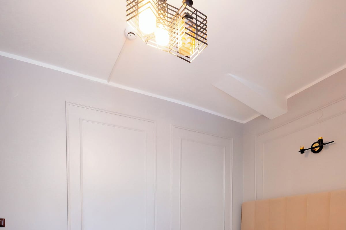 A neatly arranged bedroom with a bed, bedside table, and a hanging light fixture.