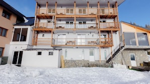 A multi-story building with balconies, a stone facade, and a snow-covered ground. - Complex Veverita  (Novaci)
