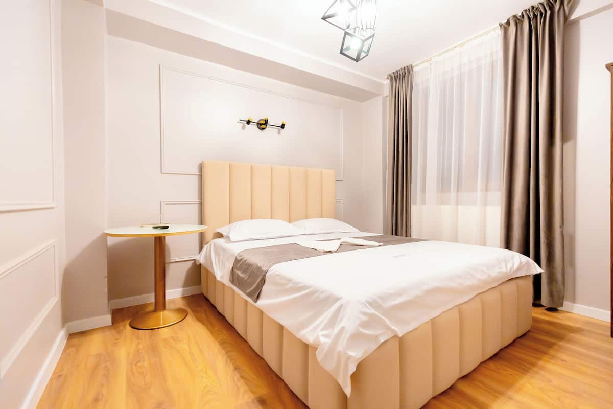A neatly arranged bedroom with a bed, bedside table, and a wall-mounted light fixture.