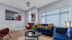 Ein modernes Wohnzimmer mit einem blauen Sofa, einem roten Sessel und einem Glastisch.