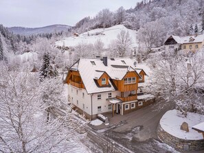A large, multi-story wooden house with a stone foundation, surrounded by snow-covered trees and a mountainous backdrop. - Holiday Apartment on Kreischberg (Sankt Georgen am Kreischberg)