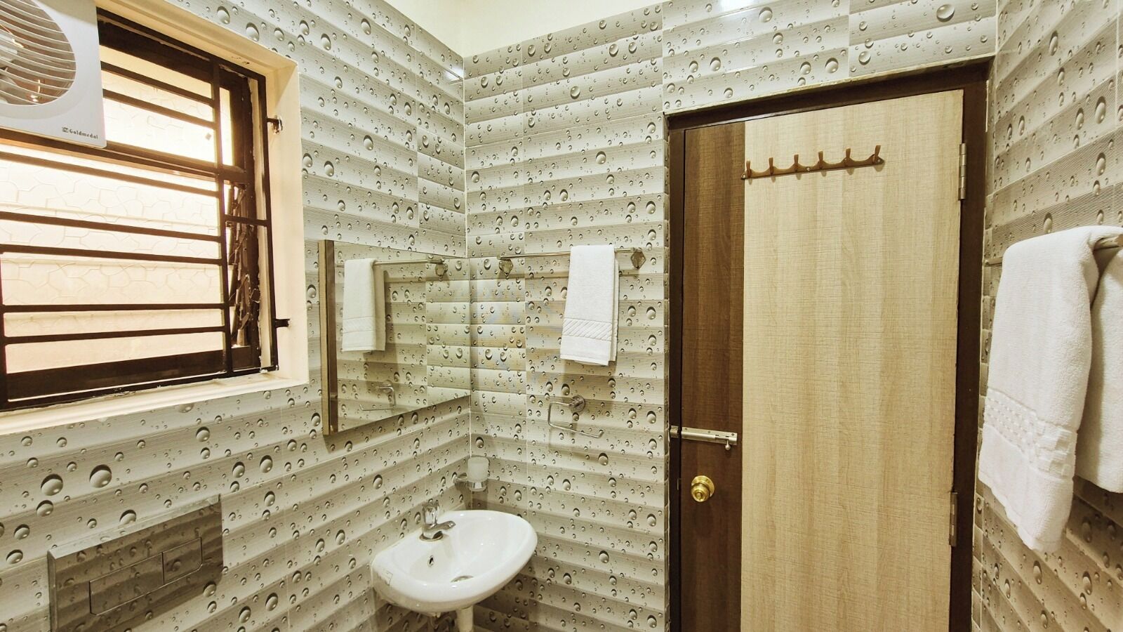 Un baño pequeño con lavamanos, espejo y ventana con barrotes.