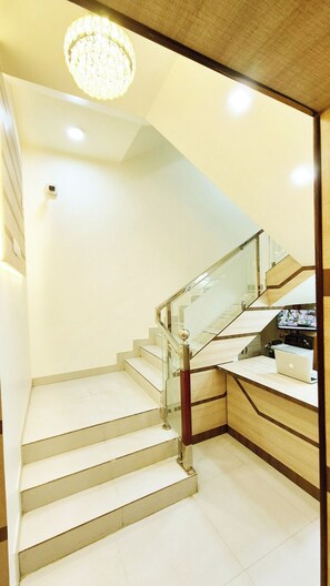 A modern staircase with glass railings and a desk area with a laptop and a telephone.