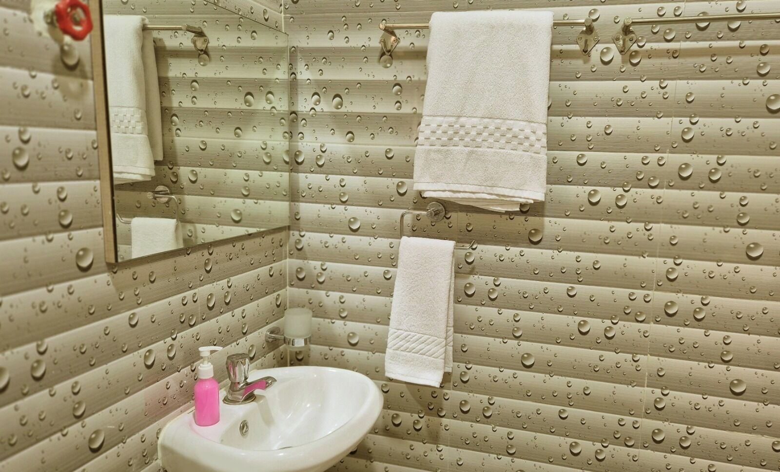 A bathroom with a sink, mirror, and two towels hanging on the wall.