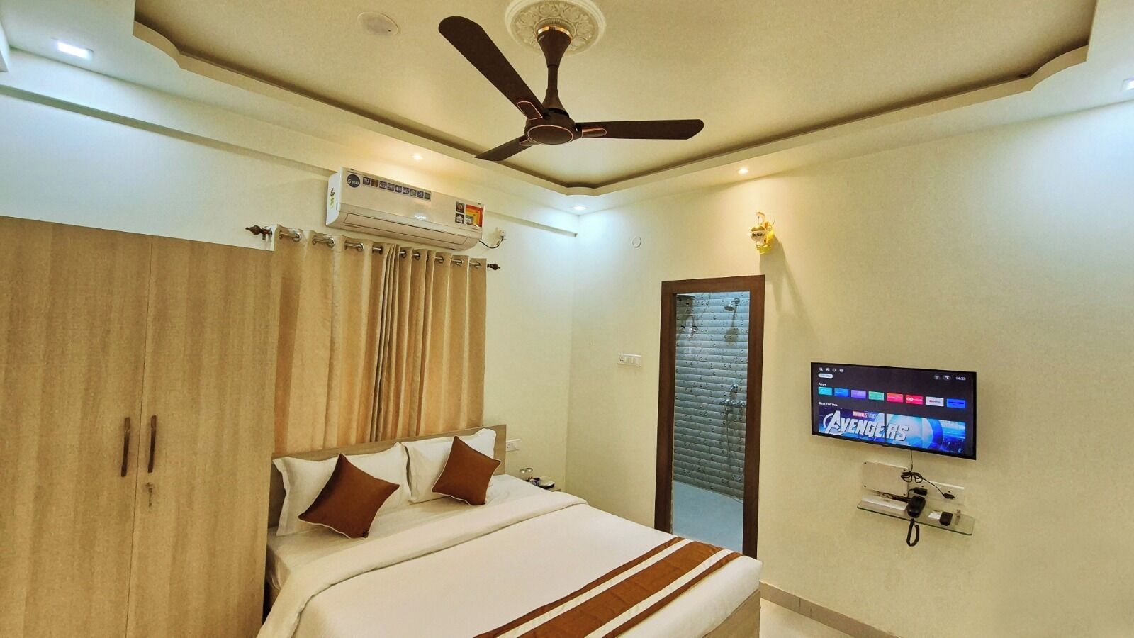 Una habitación de hotel con cama, ventilador de techo, aire acondicionado, televisor y armario.