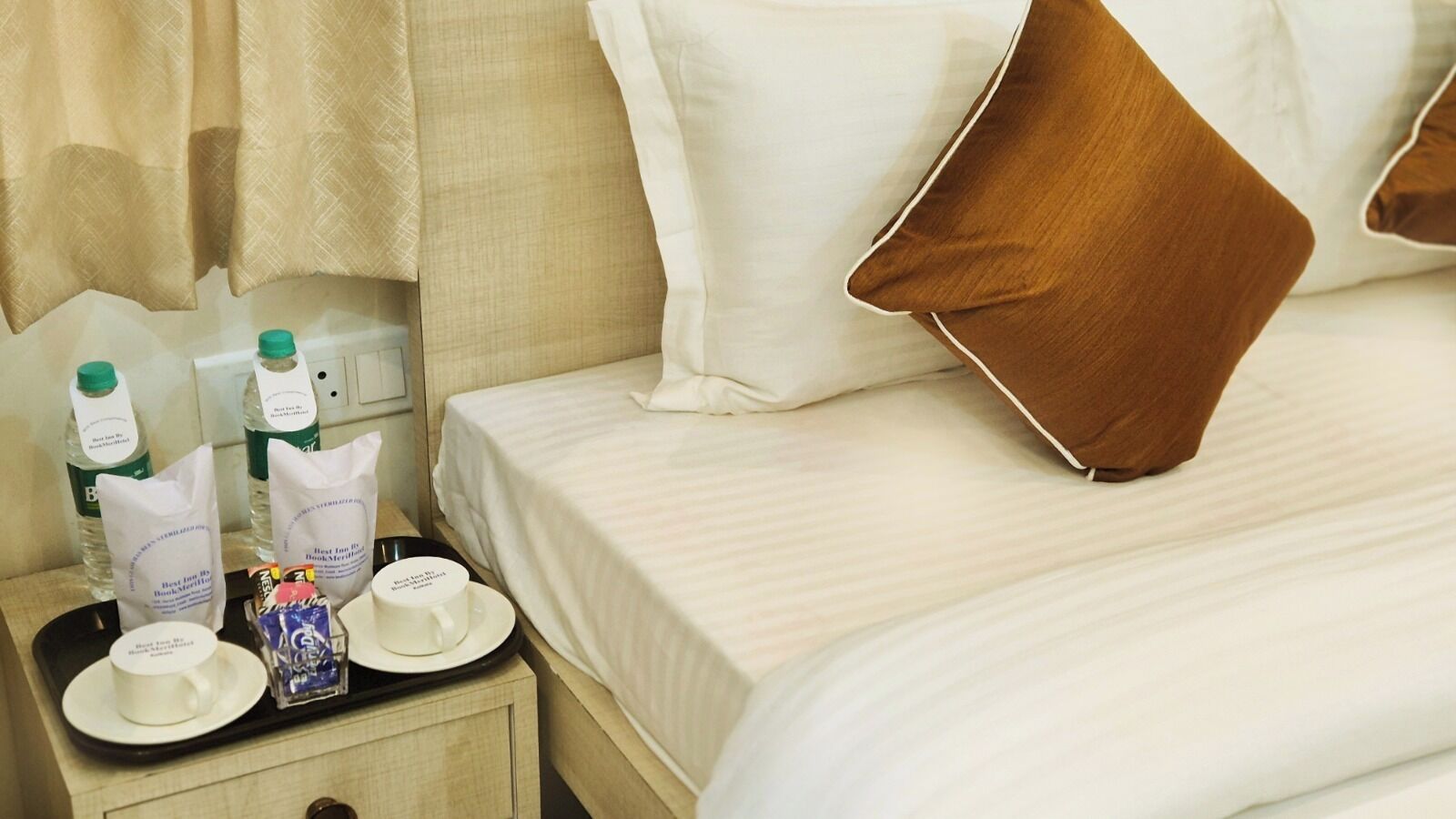 Ein Hotelzimmer mit einem ordentlich bezogenen Bett, einem Tablett mit Pflegeartikeln und einem Kissen auf dem Bett.