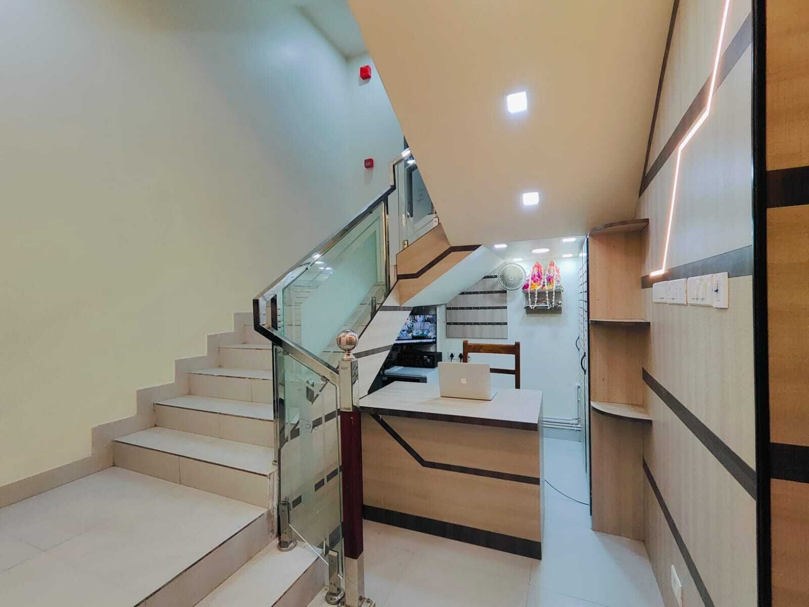 Un escalier moderne avec des rampes en verre et un espace bureau équipé d’un ordinateur portable.