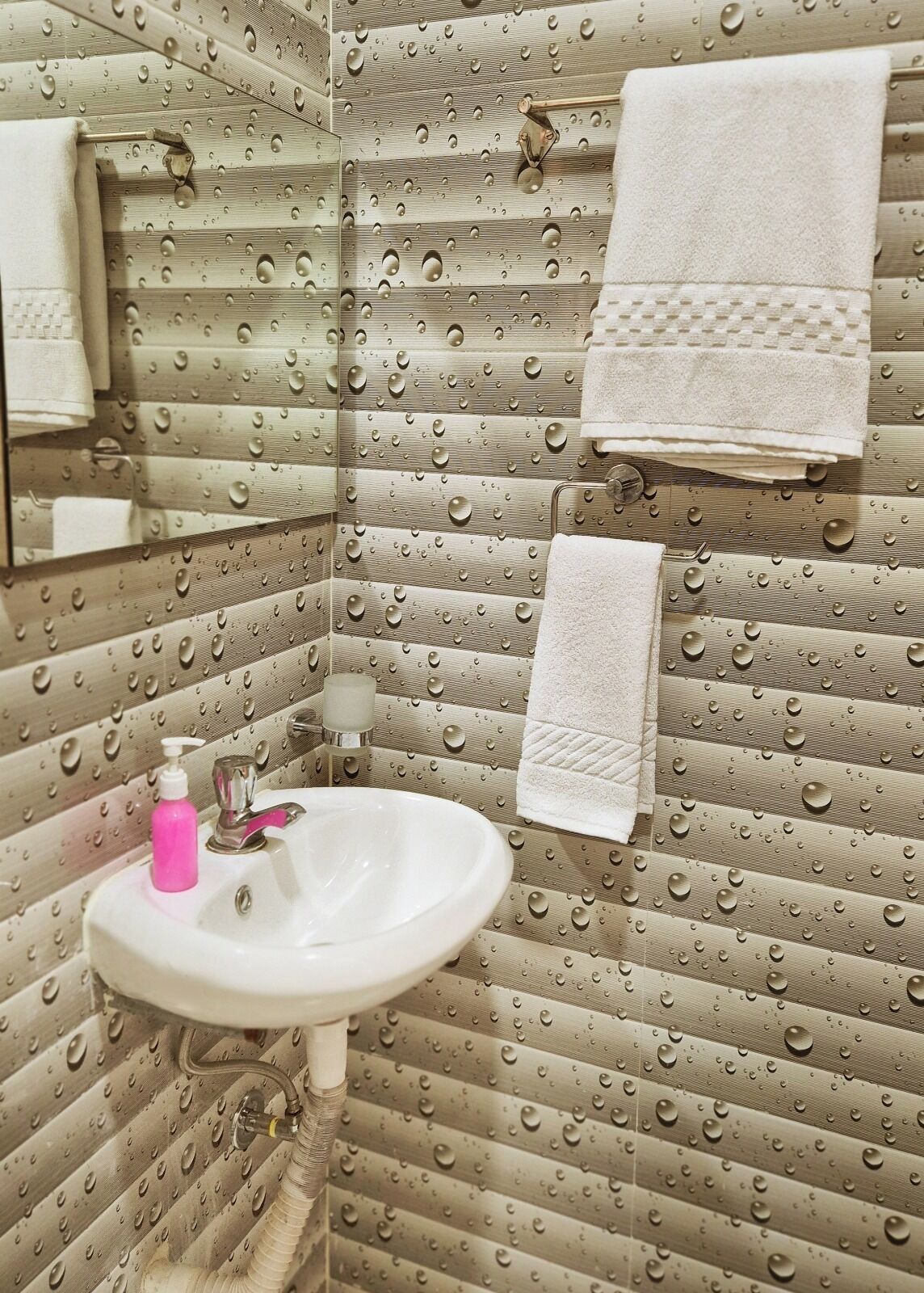 A bathroom with a sink, mirror, and towels.
