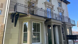 A two-story building with a balcony, large windows, and a green door.