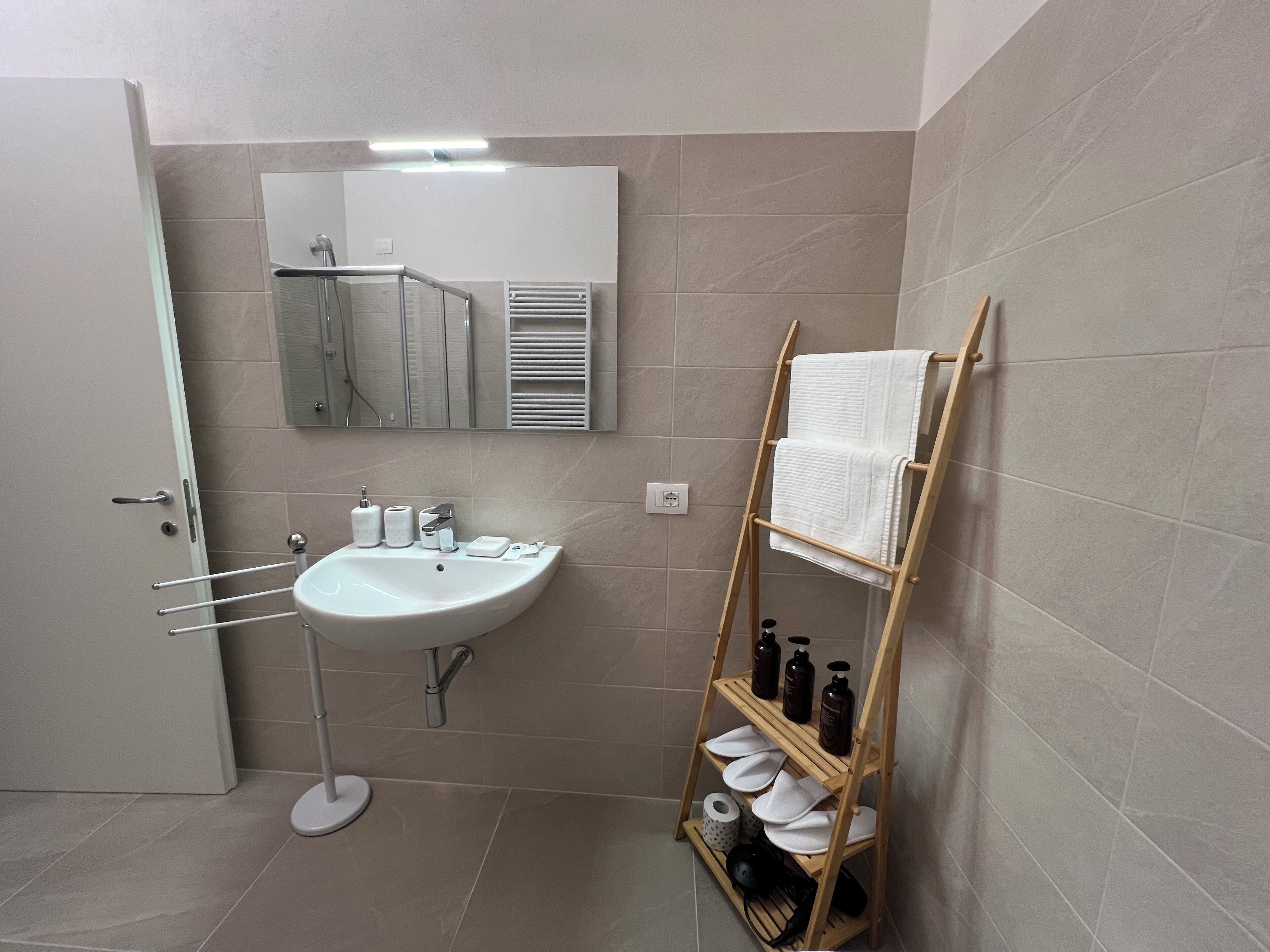A modern bathroom with a white sink, mirror, and towel rack.