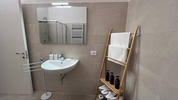 A modern bathroom with a white sink, mirror, and towel rack.
