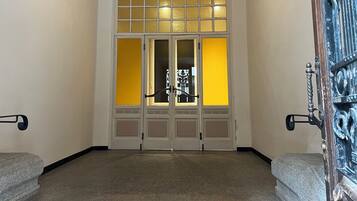 Un pasillo con un puertas dobles que incluyen un panel de vidrio decorativo y un picaporte de metal.
